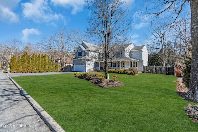 view of front of home featuring a garage, driveway, fence, and a front yard