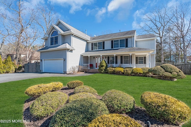 view of front facade featuring aphalt driveway, an attached garage, covered porch, fence, and a front yard