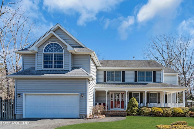 view of front facade featuring a garage, driveway, a porch, fence, and a front lawn