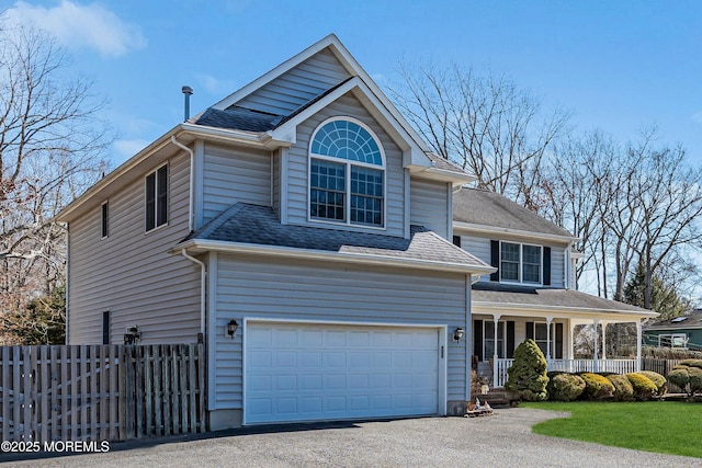 traditional-style house with a porch, a shingled roof, an attached garage, fence, and driveway