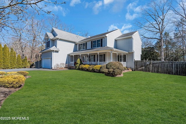 view of front facade with a front lawn, covered porch, fence, and an attached garage