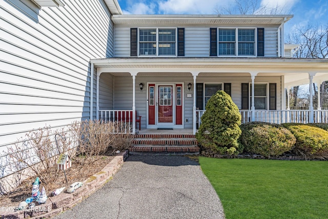 property entrance featuring a porch and a lawn