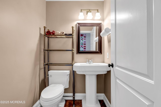 bathroom featuring baseboards, a sink, and toilet