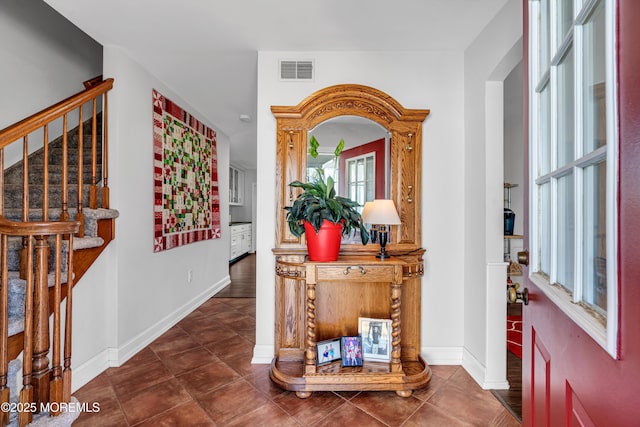 tiled entrance foyer with stairs, visible vents, and baseboards