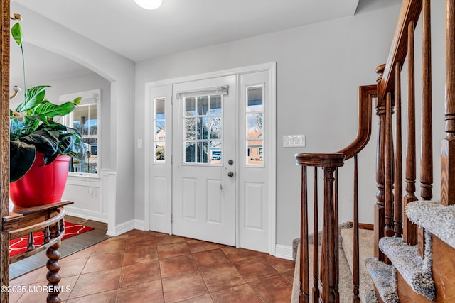 foyer with stairs, baseboards, and tile patterned floors