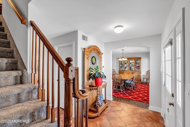 foyer entrance featuring arched walkways, visible vents, stairway, light tile patterned flooring, and baseboards