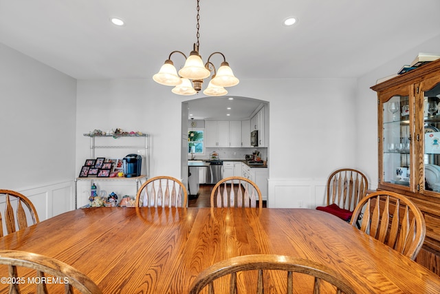 dining space with recessed lighting, a wainscoted wall, a decorative wall, and an inviting chandelier