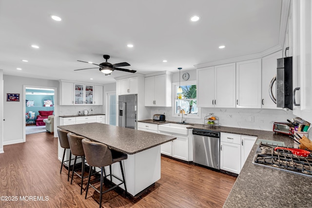 kitchen with appliances with stainless steel finishes, dark countertops, a sink, and a kitchen bar