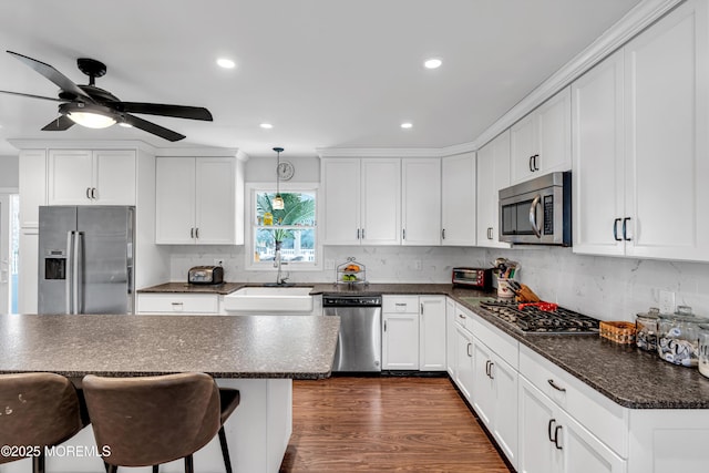 kitchen featuring appliances with stainless steel finishes, dark wood-style flooring, a sink, and tasteful backsplash