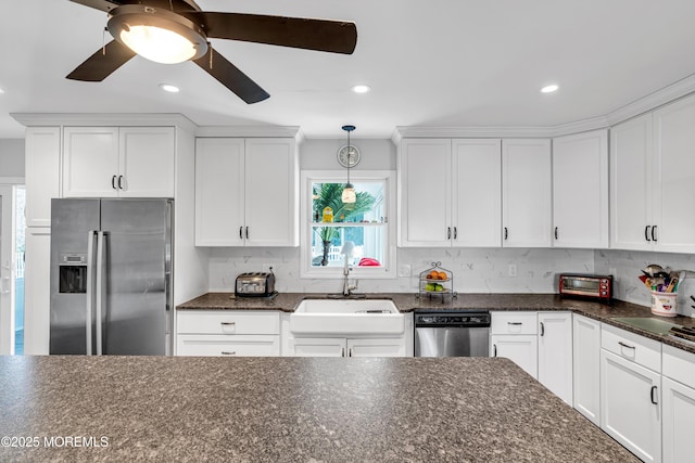 kitchen featuring appliances with stainless steel finishes, white cabinetry, a sink, and hanging light fixtures