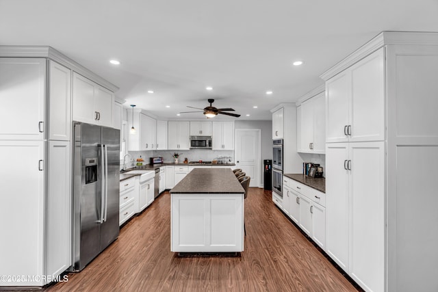 kitchen with dark countertops, white cabinets, stainless steel appliances, and a sink