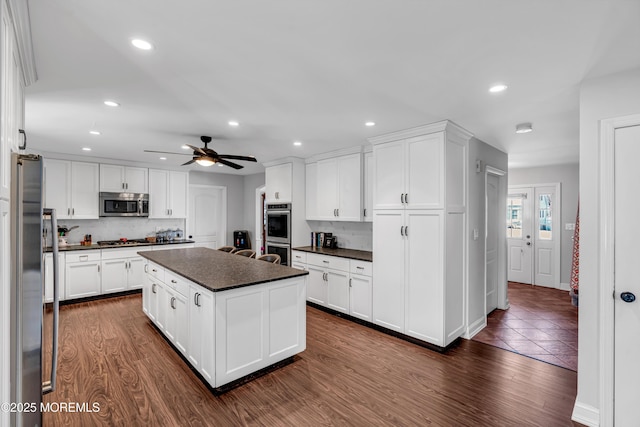 kitchen featuring appliances with stainless steel finishes, dark countertops, white cabinetry, and dark wood-style floors