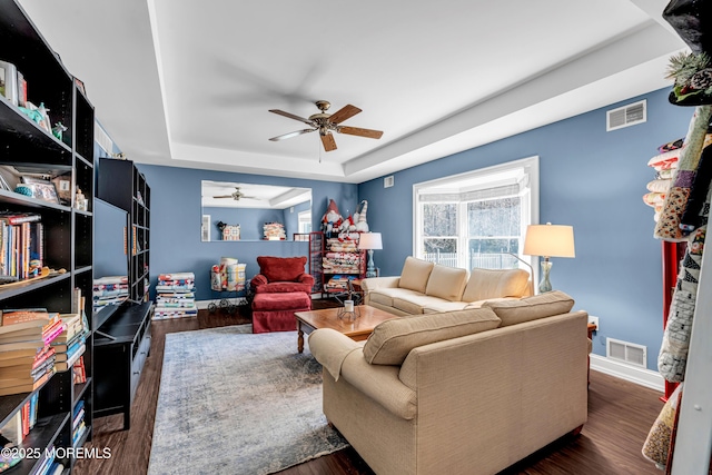 living area with visible vents, a raised ceiling, and dark wood-style flooring