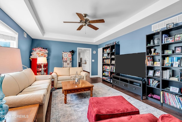 living area featuring a raised ceiling, visible vents, ceiling fan, and wood finished floors