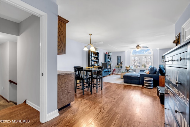 living area featuring baseboards, a ceiling fan, and wood finished floors