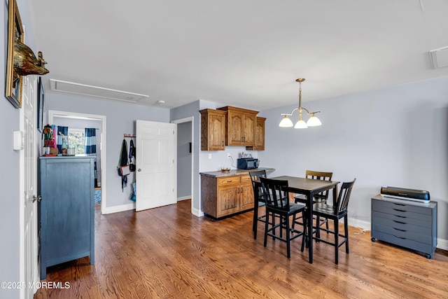 dining area with attic access, a chandelier, baseboards, and wood finished floors