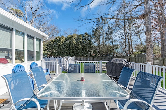 deck with outdoor dining space, a fenced backyard, and a sunroom