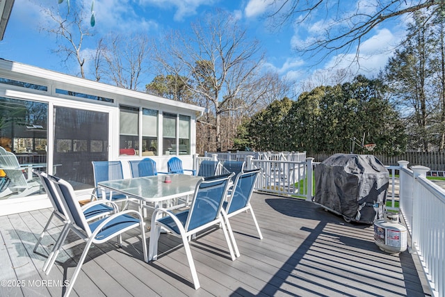 wooden terrace with outdoor dining space, a sunroom, a fenced backyard, and grilling area