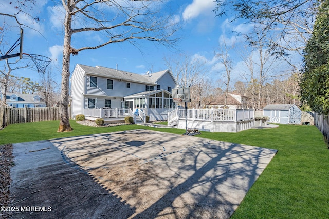 back of house with an outbuilding, a fenced backyard, a sunroom, a wooden deck, and a storage unit