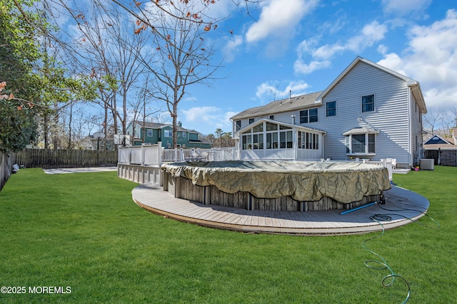 back of property featuring a yard, a fenced backyard, a sunroom, and a fenced in pool