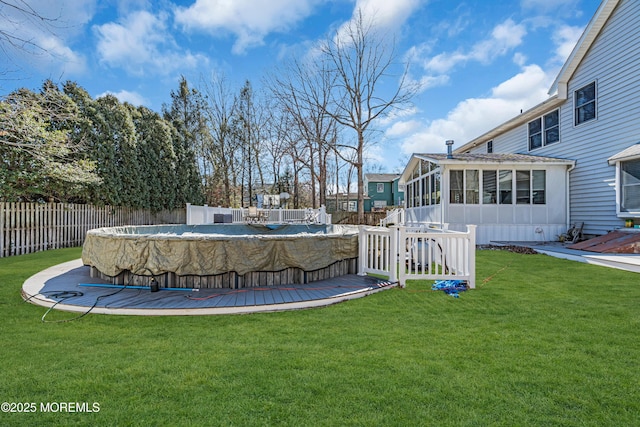 view of yard featuring a sunroom, a fenced backyard, a deck, and a fenced in pool