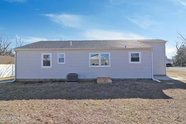 back of house with roof with shingles and central AC unit