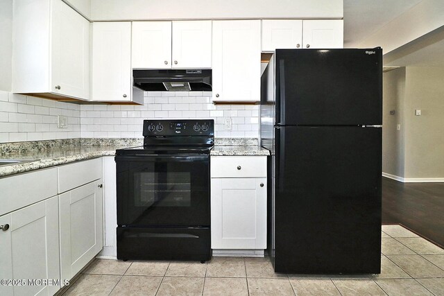 kitchen with tasteful backsplash, white cabinets, range hood, black appliances, and light tile patterned flooring