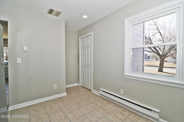 empty room featuring baseboards, visible vents, baseboard heating, and light tile patterned floors