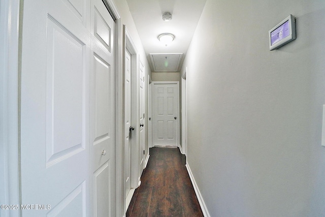 hallway with dark wood finished floors, attic access, and baseboards