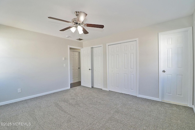 unfurnished bedroom featuring carpet, multiple closets, visible vents, ceiling fan, and baseboards