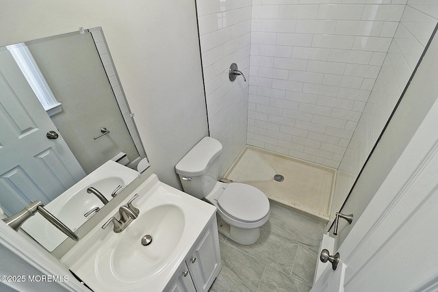 full bathroom with a tile shower, vanity, and toilet