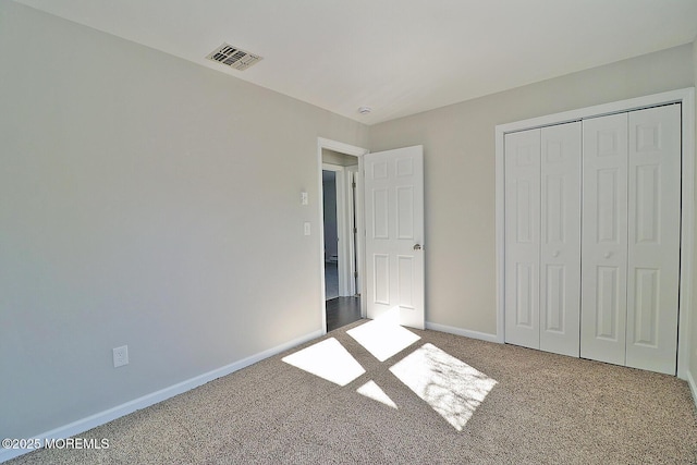 unfurnished bedroom featuring carpet, a closet, visible vents, and baseboards