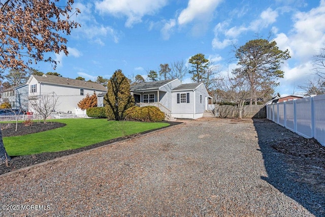 view of front of property featuring a front lawn, gravel driveway, and fence