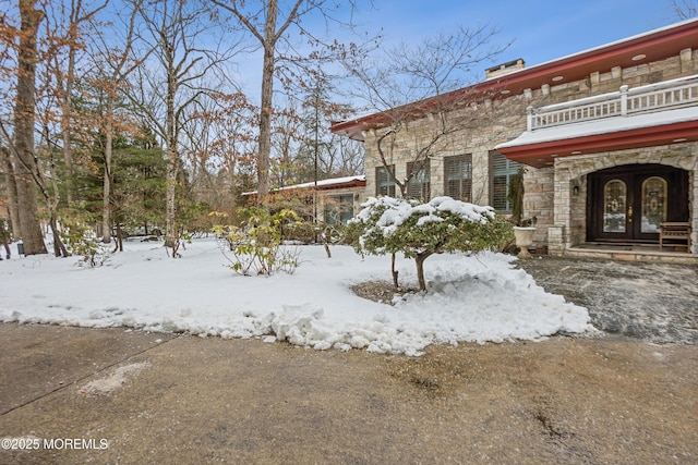 exterior space with stone siding, french doors, and a balcony