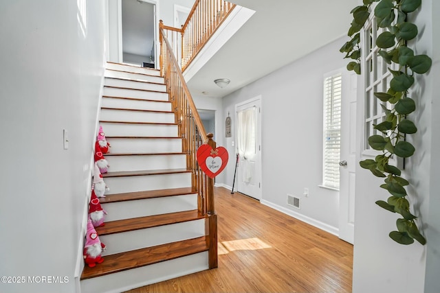 stairs featuring wood finished floors, visible vents, and baseboards