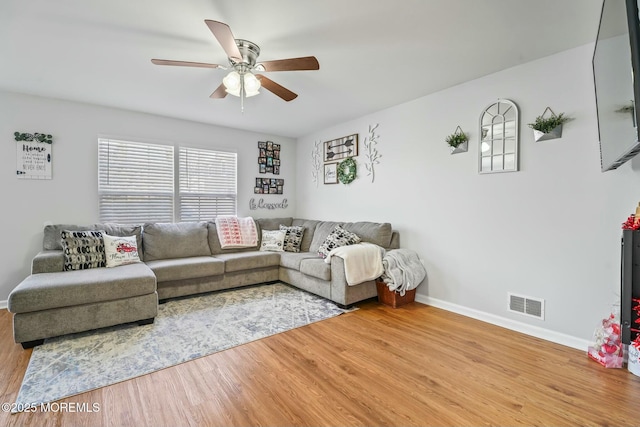 living area with visible vents, ceiling fan, baseboards, and wood finished floors