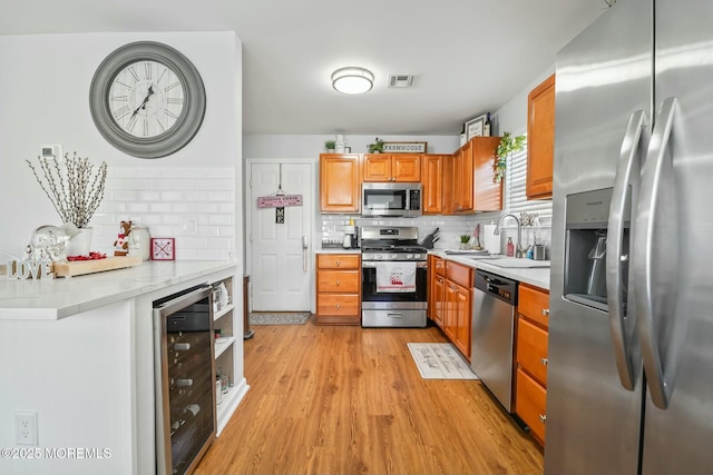 kitchen with beverage cooler, stainless steel appliances, a sink, visible vents, and light countertops