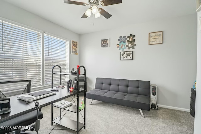 carpeted office space featuring a ceiling fan and baseboards