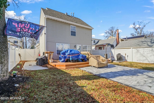 rear view of property featuring a fenced backyard, a deck, a lawn, and a patio