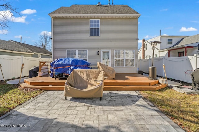 back of property with a fenced backyard, a wooden deck, and a patio