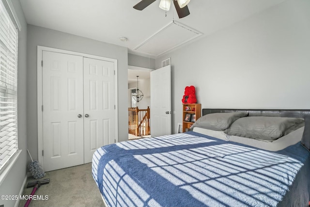 bedroom with ceiling fan, visible vents, a closet, carpet, and attic access