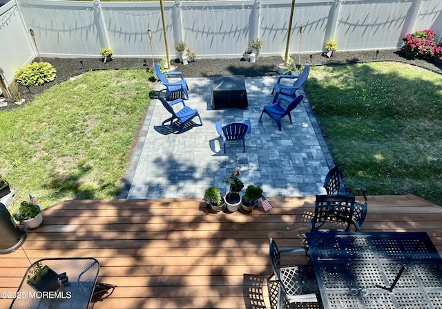 wooden terrace with a fire pit, a yard, fence, and a patio