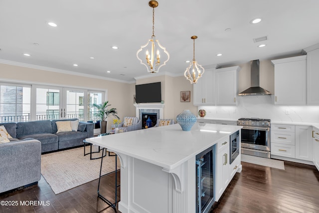 kitchen featuring stainless steel appliances, wine cooler, wall chimney exhaust hood, open floor plan, and a center island