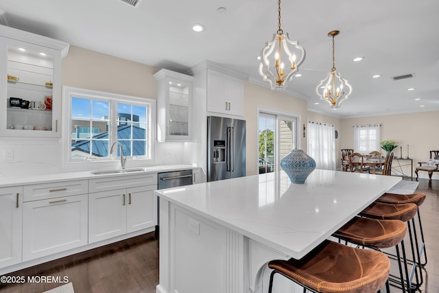 kitchen featuring a sink, a center island, stainless steel appliances, glass insert cabinets, and a chandelier