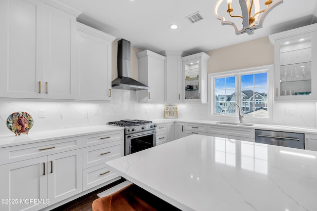 kitchen with visible vents, backsplash, appliances with stainless steel finishes, wall chimney exhaust hood, and a sink