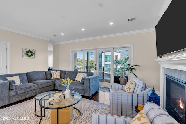 living room with a glass covered fireplace, wood finished floors, french doors, and ornamental molding