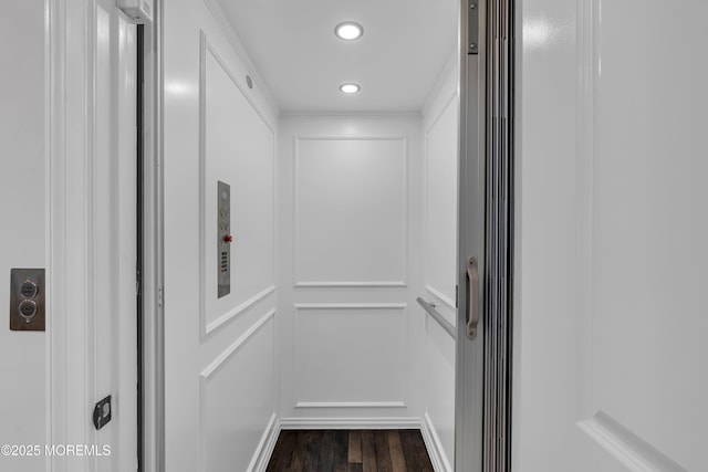 interior details with recessed lighting, elevator, wood finished floors, and a decorative wall