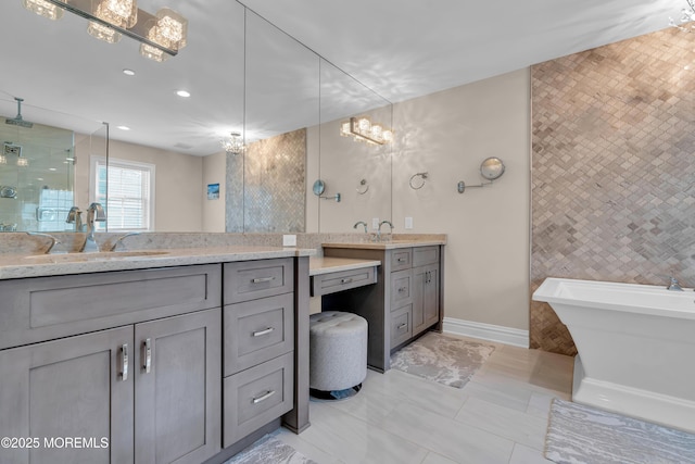 full bathroom featuring baseboards, a soaking tub, two vanities, a stall shower, and a sink