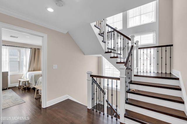 staircase with a wealth of natural light, visible vents, baseboards, and wood finished floors