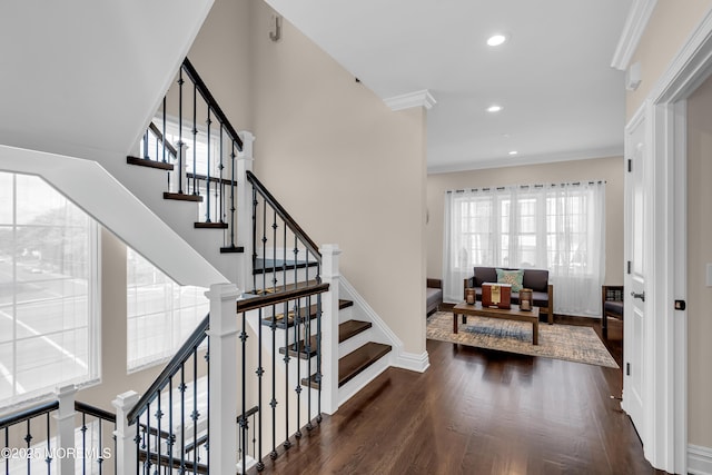 stairs featuring wood finished floors, recessed lighting, a high ceiling, crown molding, and baseboards